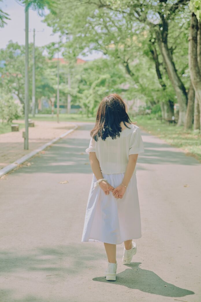 Photo by Tri Vo woman in white dress walking on road during daytime