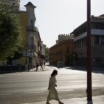 스트레스, 일상 속 작은 변화로 관리하세요 A woman walking down a street next to tall buildings