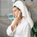 저속노화 시대! 손쉬운 노화 방지 비결 a woman with a towel on her head is looking at her cell phone